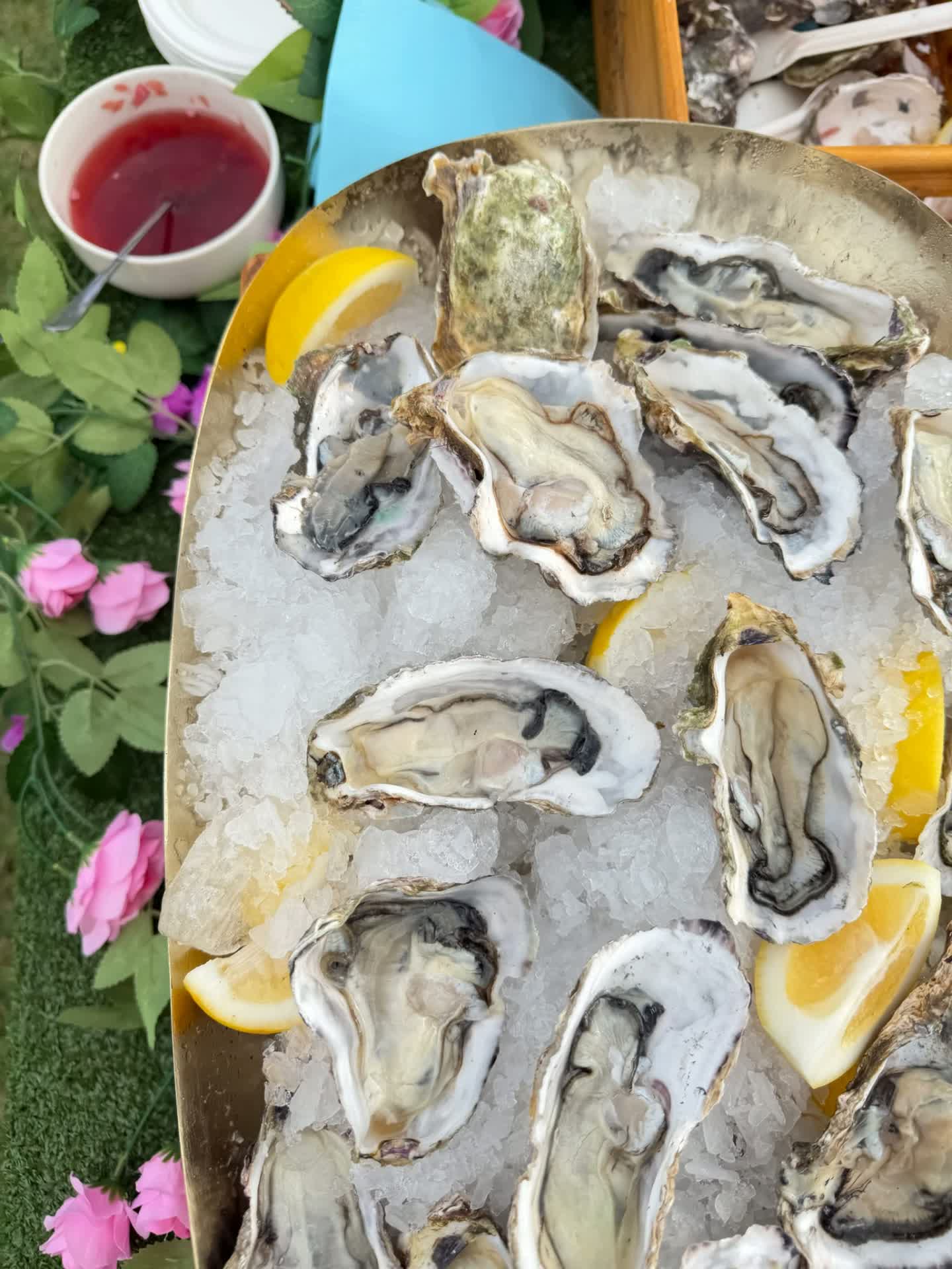 Brass platter of shucked oysters on ice with lemon and mignonette